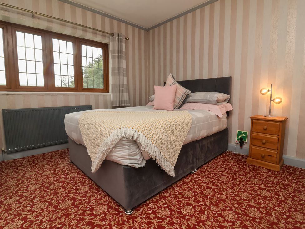 A bedroom with a bed and windows at West Down Country House in South Molton