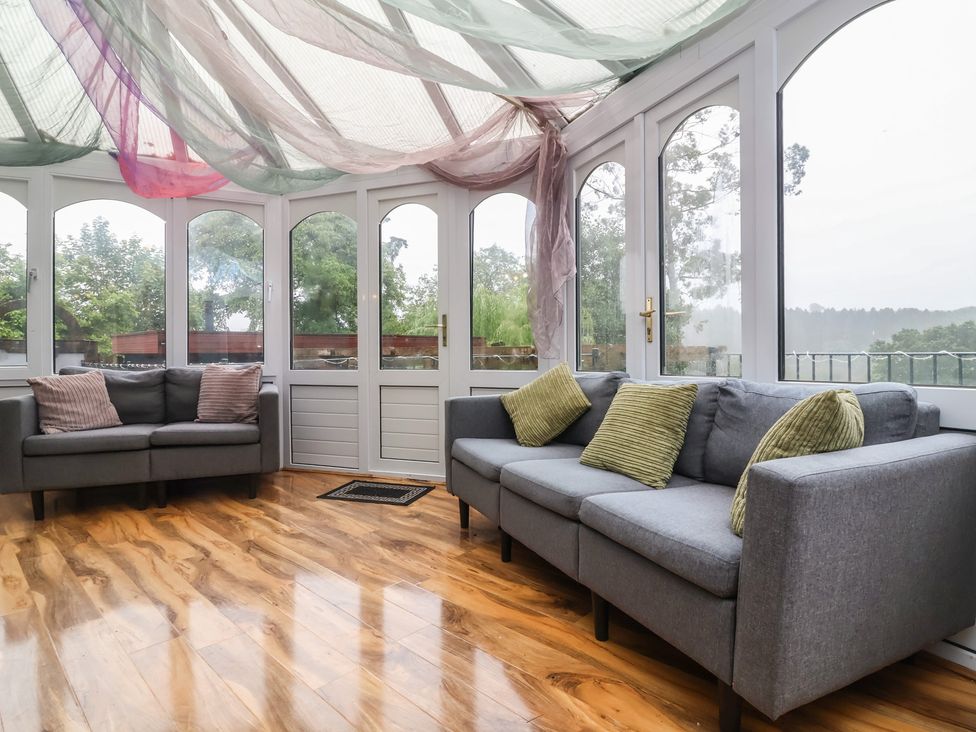A conservatory with sofas and large windows at West Down Country House in South Molton