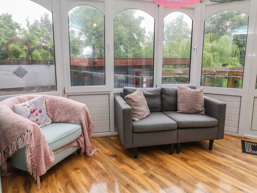 A conservatory with seating and large windows at West Down Country House in South Molton
