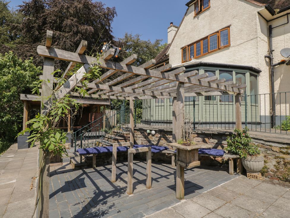 An outdoor seating area with a pergola and benches at West Down Country House in South Molton