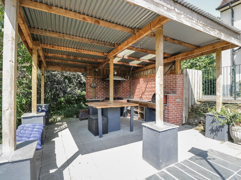 An outdoor kitchen shelter with a table and benches at West Down Country House in South Molton
