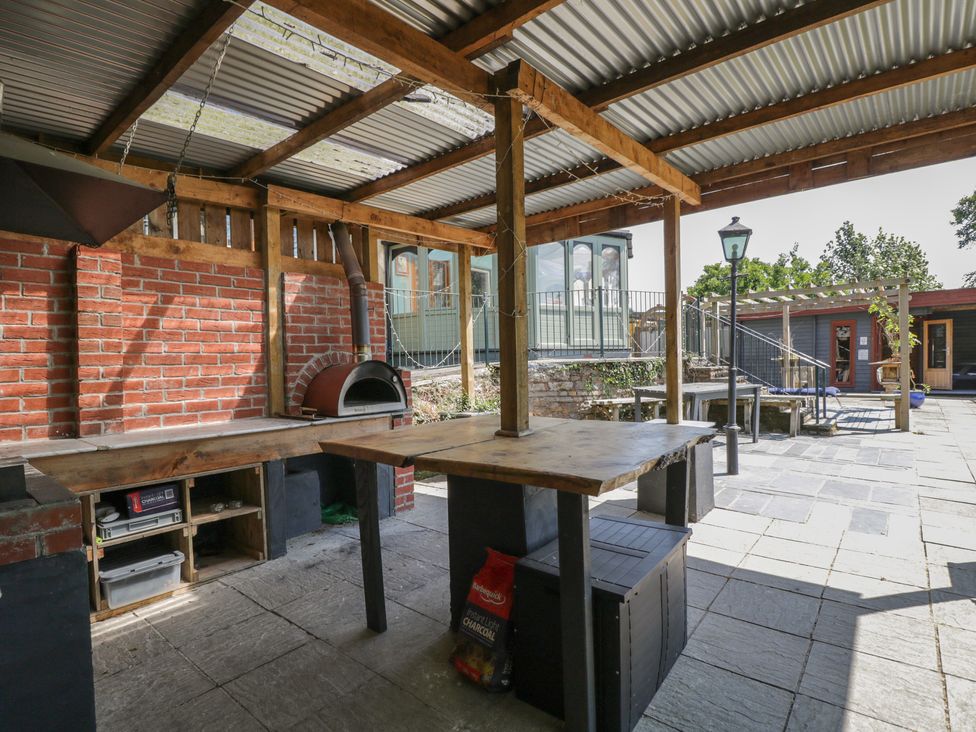 An outdoor kitchen with wooden table and pizza oven at West Down Country House in South Molton