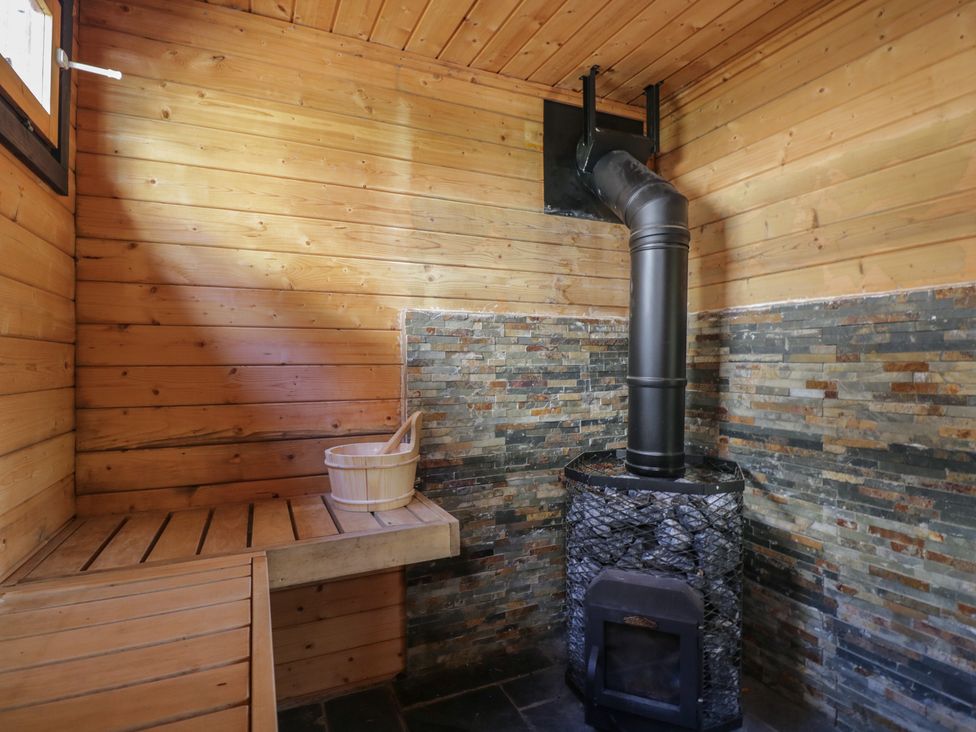 A sauna with a wooden bench and stove at West Down Country House in South Molton
