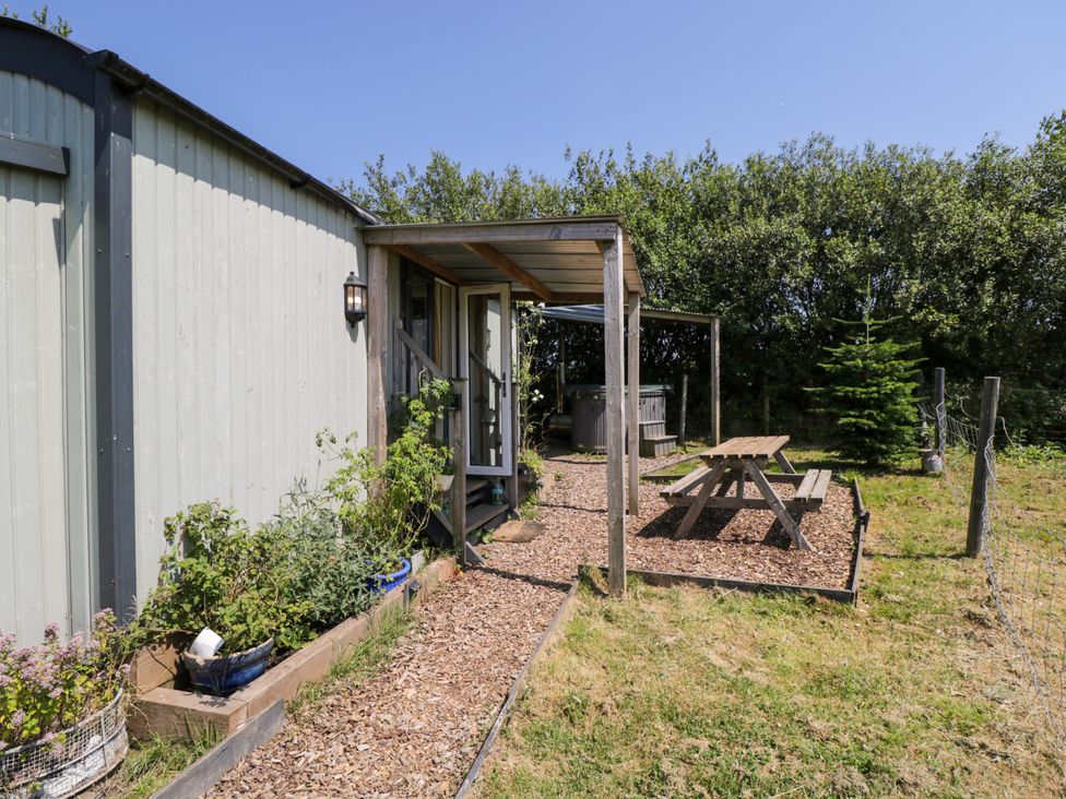 An outdoor area with a hut, table, and chairs at Daisy Shepherd's Hut in South Molton