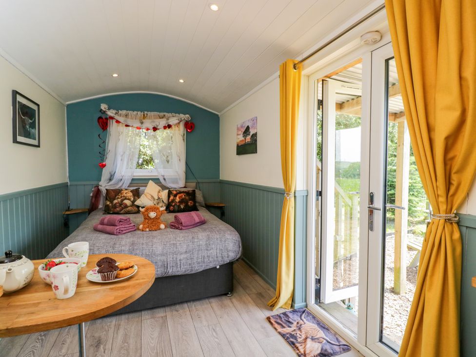 A bedroom with a bed and coffee table at Daisy Shepherd's Hut in South Molton