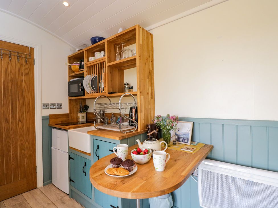 A kitchen with a sink, counter, and seating at Daisy Shepherd's Hut South Molton