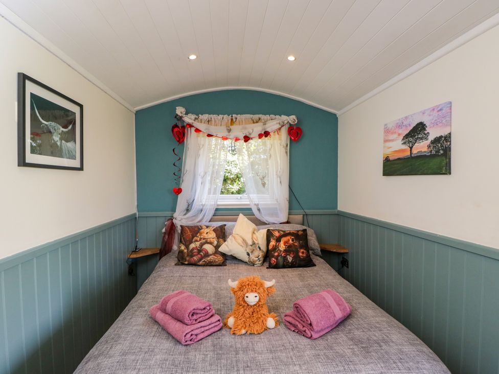 A bedroom with a bed and decorative items at Daisy Shepherd's Hut in South Molton