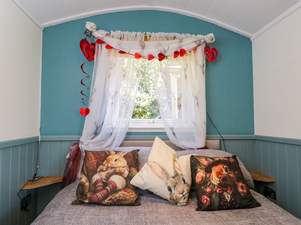 A bedroom with a bed and decorative pillows at Daisy Shepherd's Hut South Molton