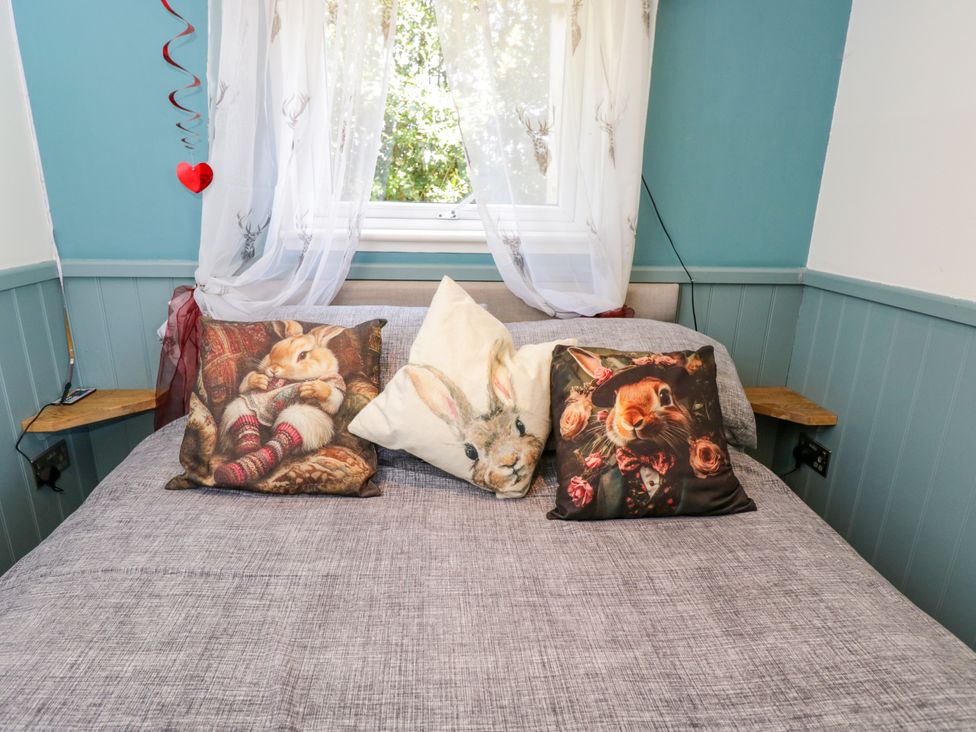 A bed with decorative pillows at Daisy Shepherd's Hut in South Molton