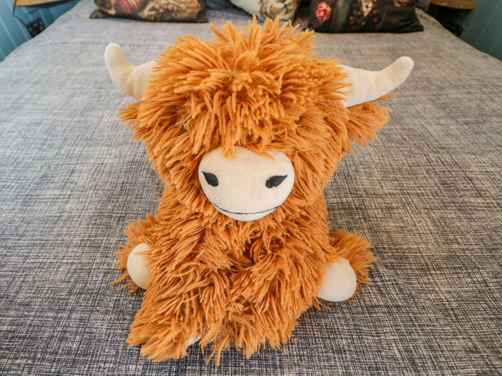 A plush toy in the shape of a cow on a bed at Daisy Shepherd's Hut in South Molton