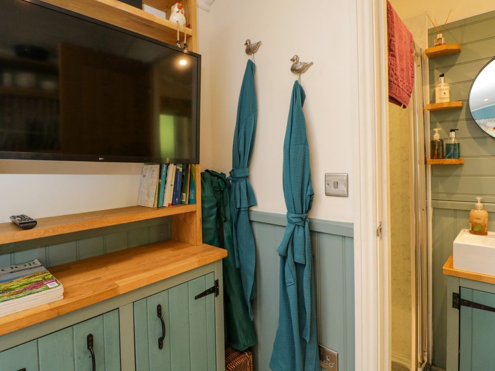A bathroom with a television and towels at Daisy Shepherd's Hut in South Molton