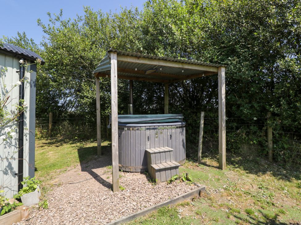 A hot tub under a shelter in an outdoor area at Daisy Shepherd's Hut South Molton