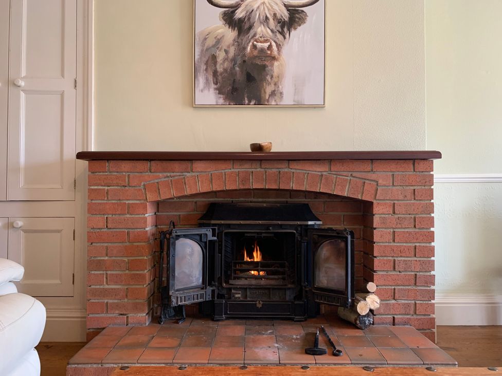 A fireplace with fire and artwork at Highfields in Caunton near Southwell
