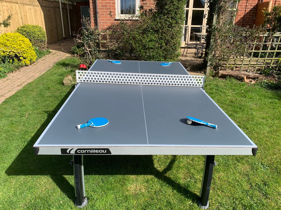 A ping pong table with paddles and a ball in the garden at Highfields in Caunton near Southwell