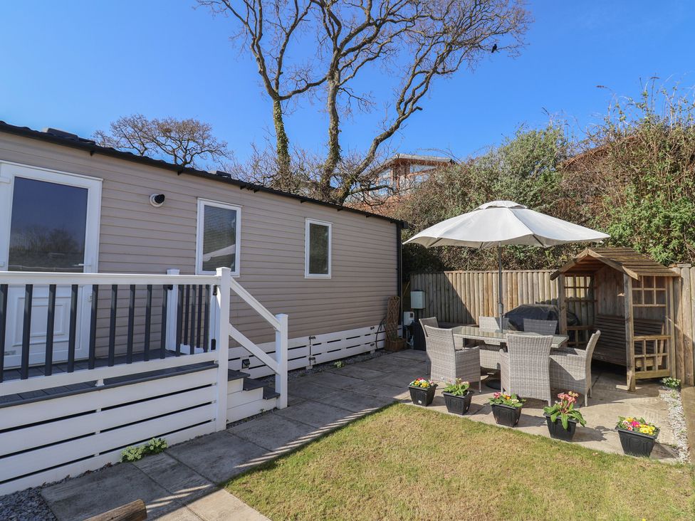 An outdoor seating area with a table, chairs, and umbrella at Bordeaux Ladram Bay Otterton