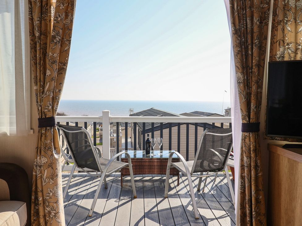 A balcony with chairs and a table overlooking the sea at Bordeaux in Ladram Bay Otterton
