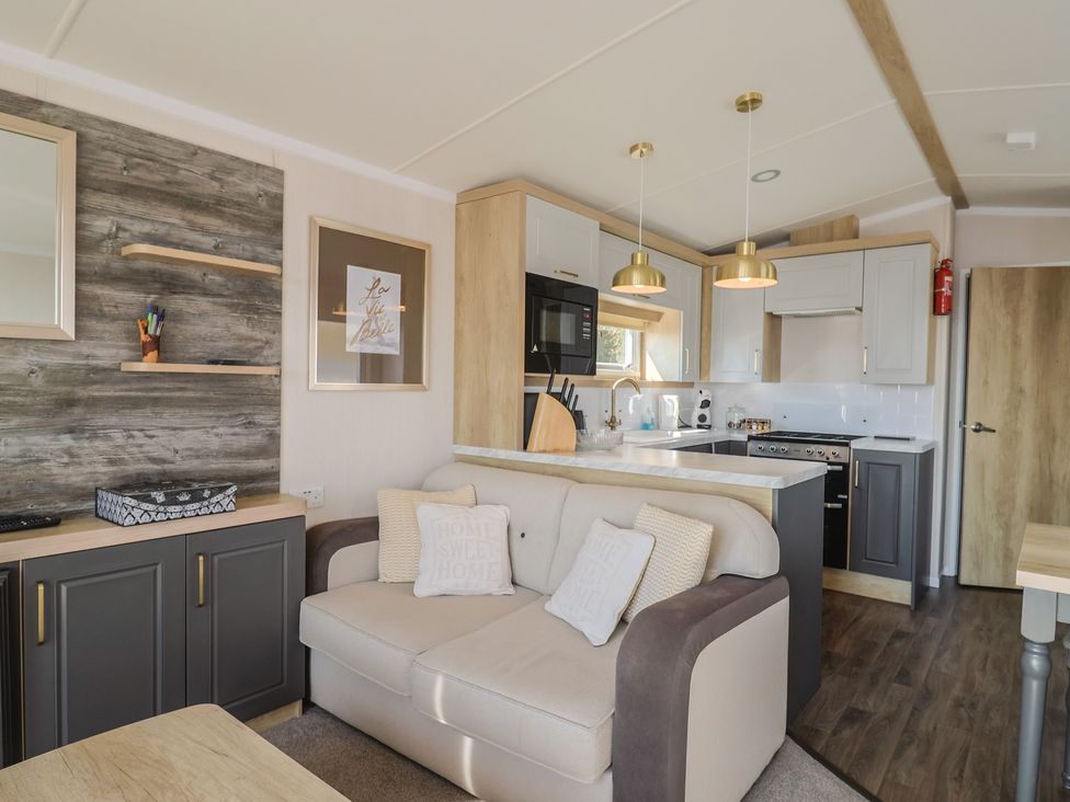 A living room with a sofa and kitchen appliances at Bordeaux in Ladram Bay Otterton