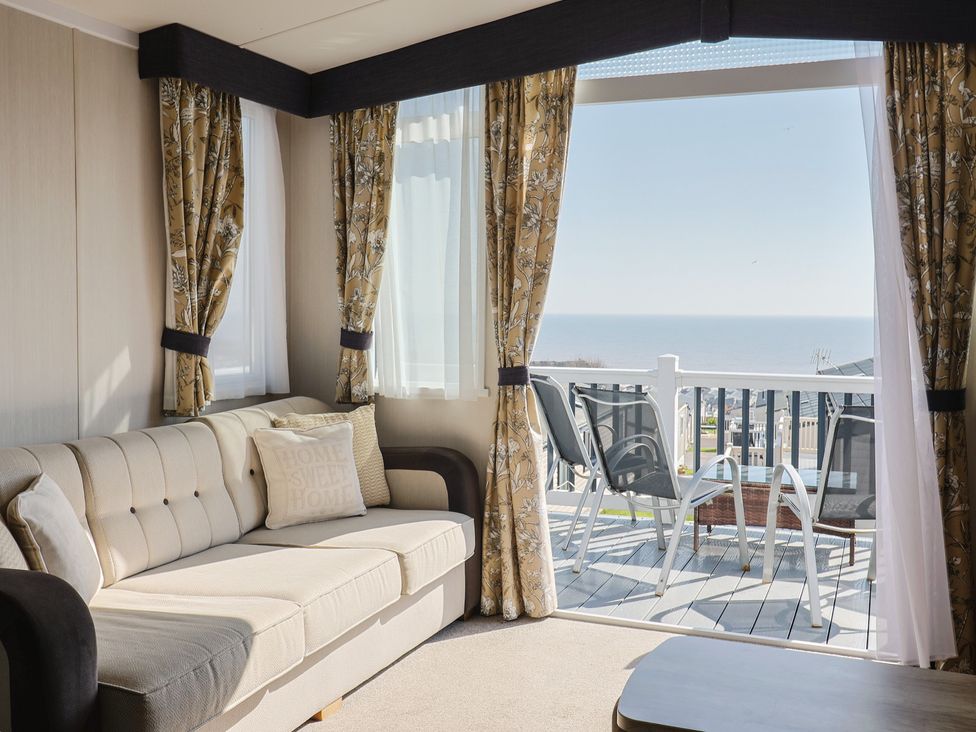 A living room with a sofa and a view of the sea at Bordeaux in Ladram Bay Otterton