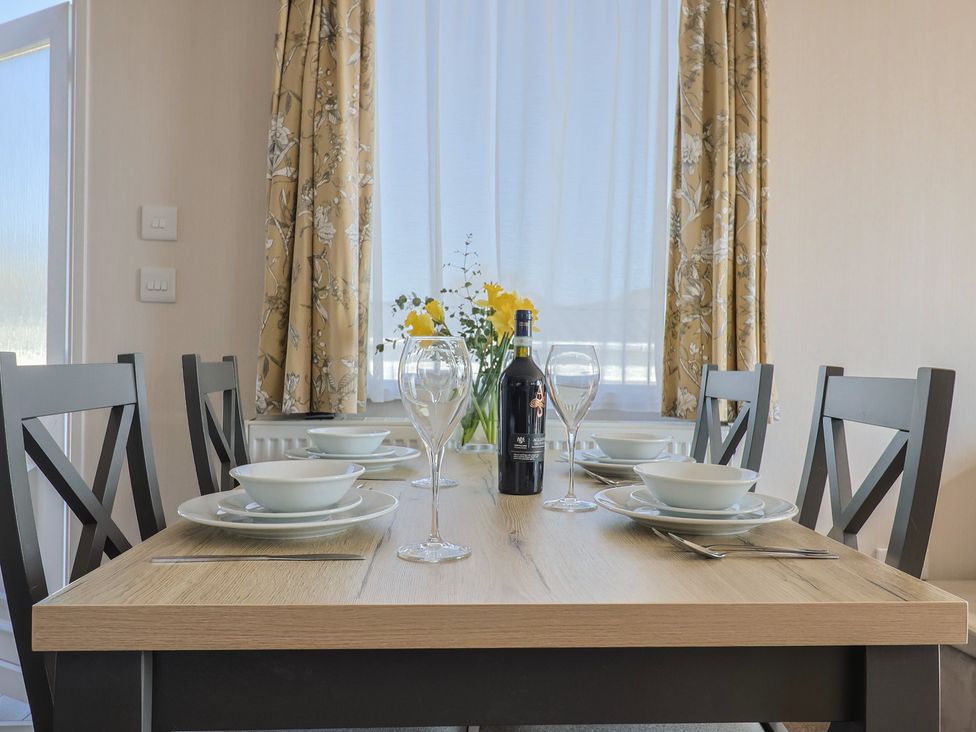 A dining room with a table set for a meal at Bordeaux in Ladram Bay Otterton