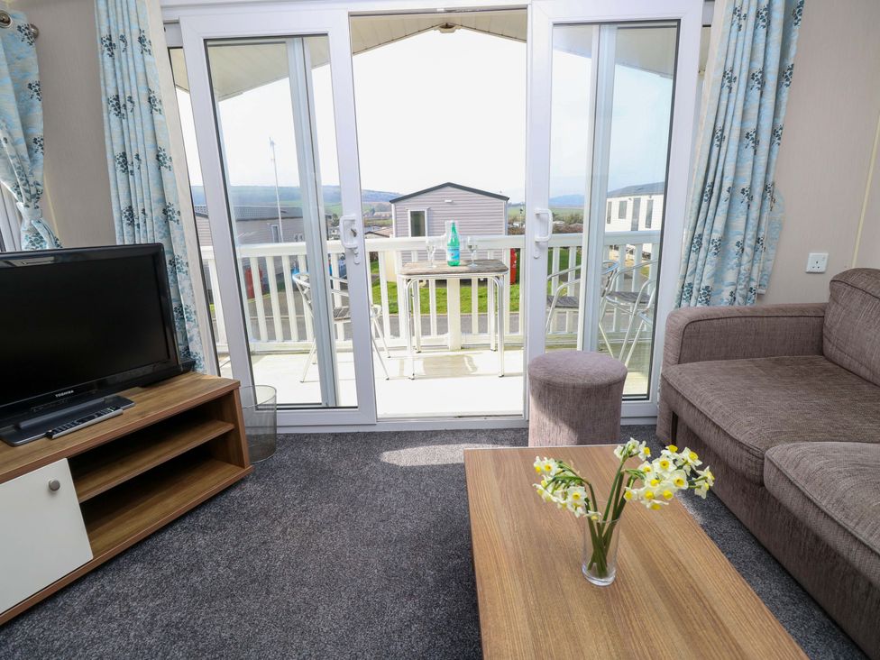 A living room with a television and sliding door at 63 Crosswinds in Bembridge