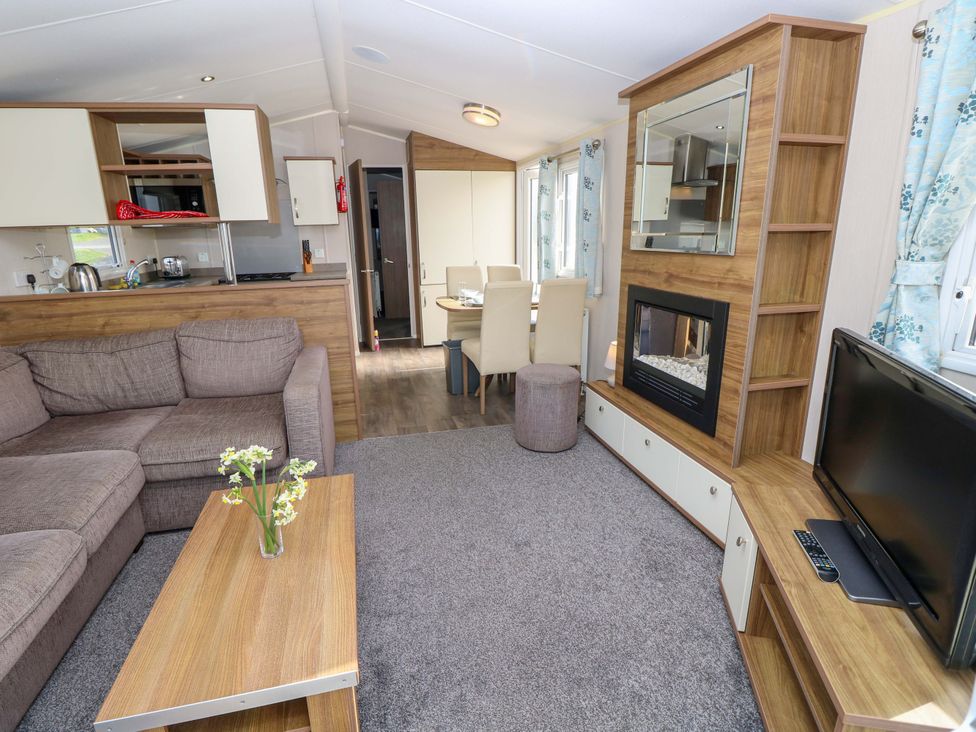 A living room with a sofa, coffee table, and television at 63 Crosswinds in Bembridge