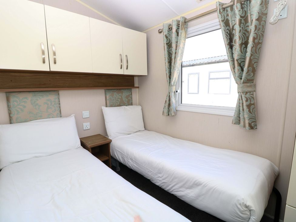A bedroom with two beds and a window at 63 Crosswinds in Bembridge