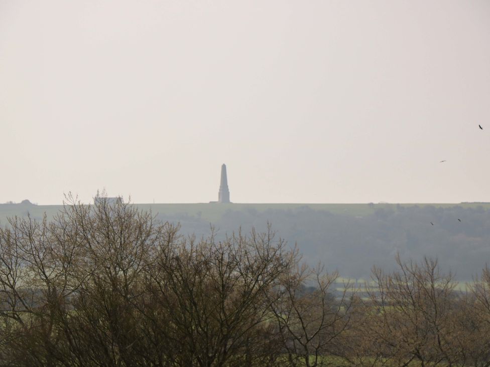 A distant monument on a hill with trees and a cloudy sky at 63 Crosswinds in Bembridge