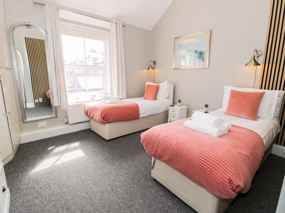 A bedroom with two beds and a mirror at The Causeway in Llandudno