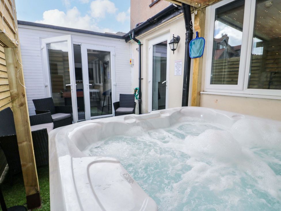 A hot tub with chairs and glass doors in an outdoor area at The Causeway Llandudno