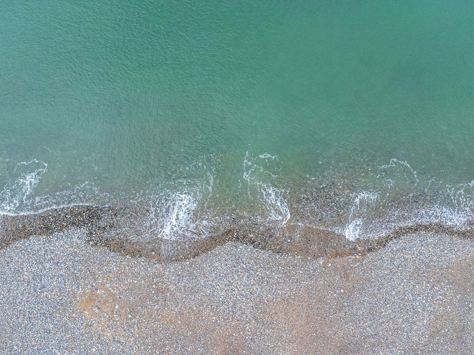 A shoreline with water and pebbles at The Causeway in Llandudno