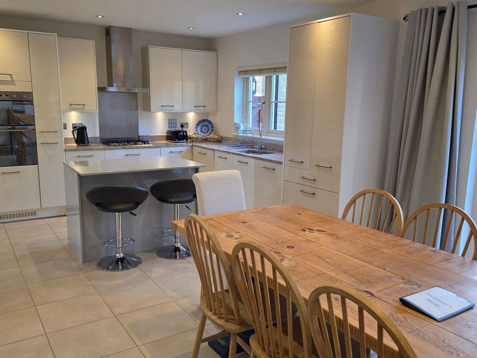 A kitchen with an island and dining table at Spacious 4-Bedroom Cotswold Home in Lechlade