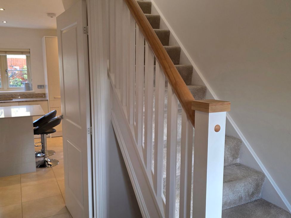 A hallway with a staircase and bar stools at Spacious 4-Bedroom Cotswold Home in Lechlade