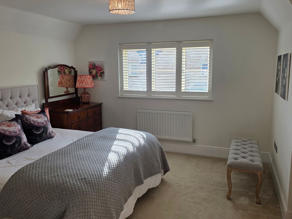 A bedroom featuring a bed, mirror, and chest of drawers at Spacious 4-Bedroom Cotswold Home in Lechlade