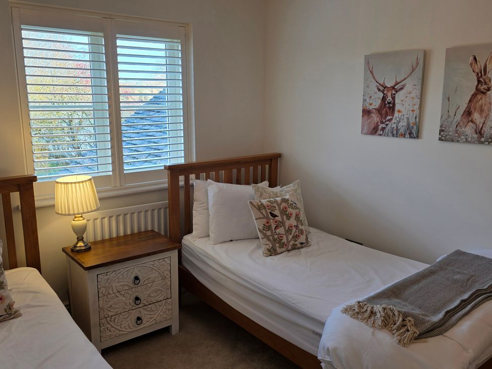 A bedroom with two beds and a side table at Spacious 4-Bedroom Cotswold Home in Lechlade