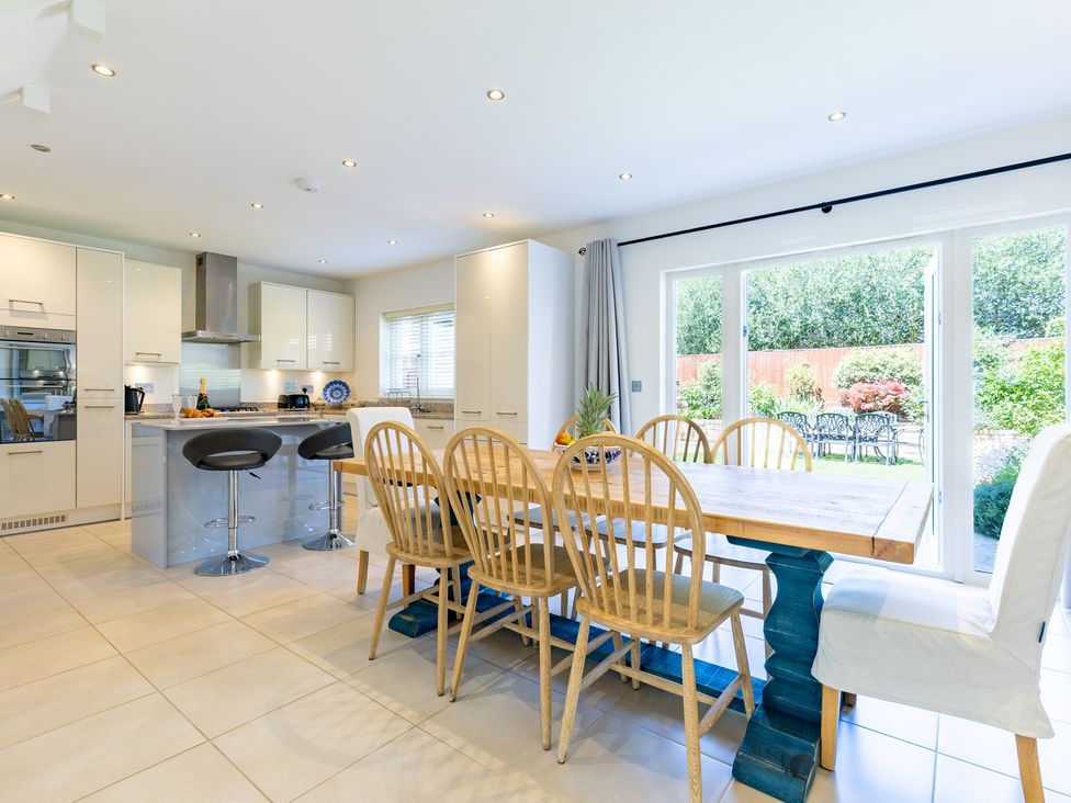 A kitchen with a dining table and bar stools at Old Railway Close in Lechlade-On-Thames