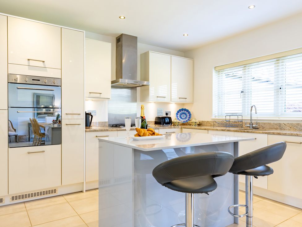 A kitchen with cabinets, countertop, and bar stools at Old Railway Close Lechlade-On-Thames