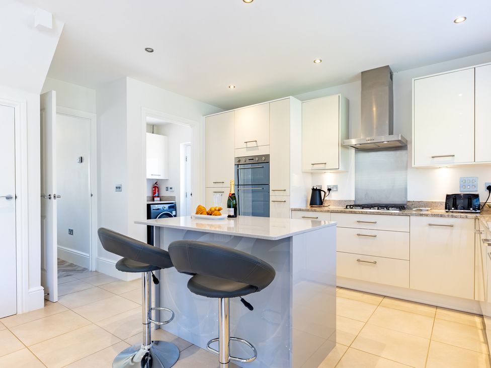 A kitchen with bar stools and appliances at Old Railway Close in Lechlade-On-Thames