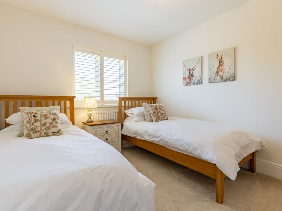 A bedroom with two beds and paintings at Old Railway Close Lechlade-On-Thames