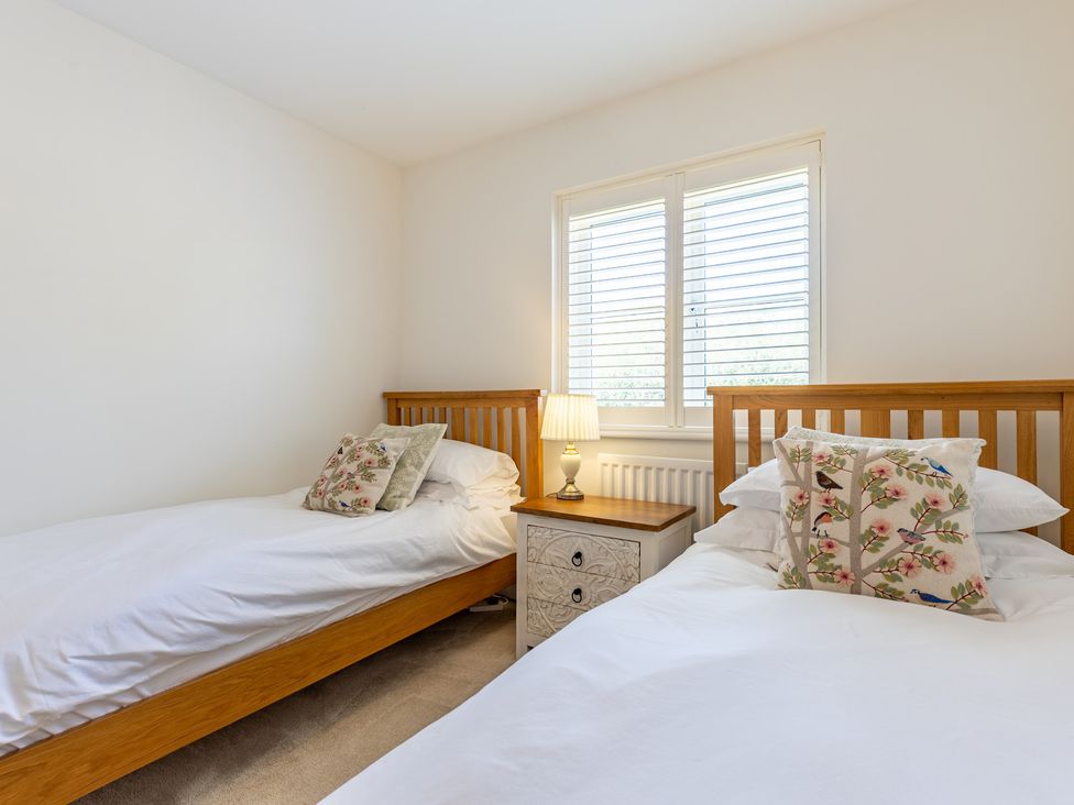 A bedroom with two beds and a lamp on a nightstand at Old Railway Close in Lechlade-On-Thames