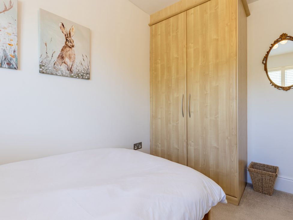 A bedroom with a wardrobe and wall art at Old Railway Close in Lechlade-On-Thames