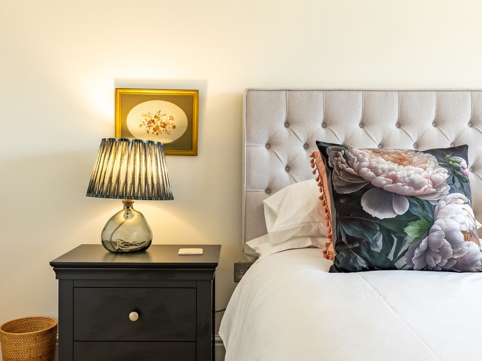 A bedroom with a lamp and flower pillow at Old Railway Close in Lechlade-On-Thames