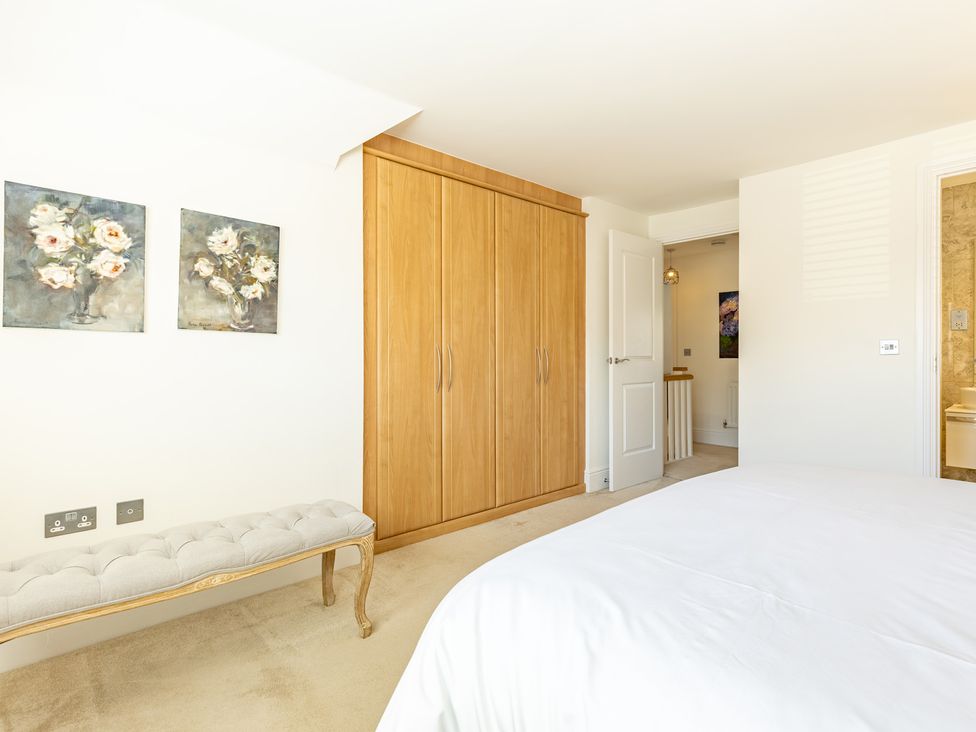A bedroom featuring a wardrobe and paintings at Old Railway Close, Lechlade-On-Thames