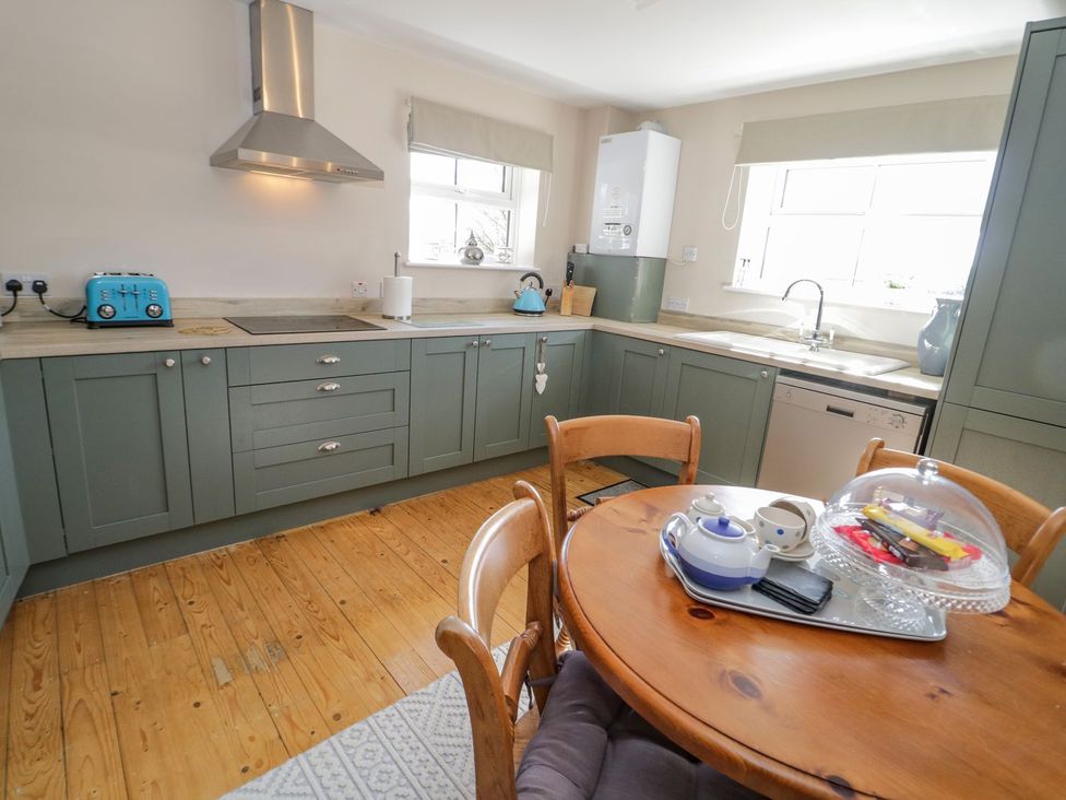 A kitchen with cabinets, a sink, and a round table at Eryri View Retreat