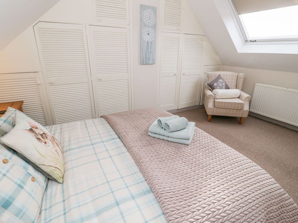 A bedroom with a bed and armchair at Eryri View Retreat
