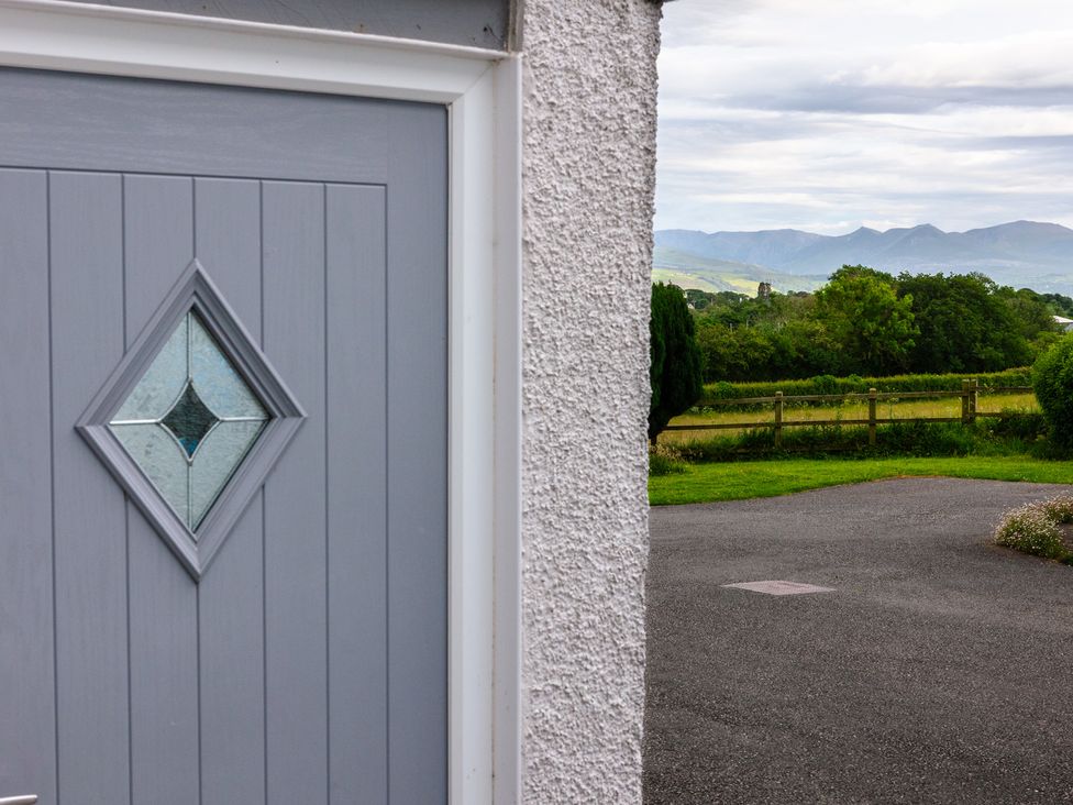 A door with a diamond window and a view of trees and fields at Eryri View Retreat in Llangoed near Beaumaris