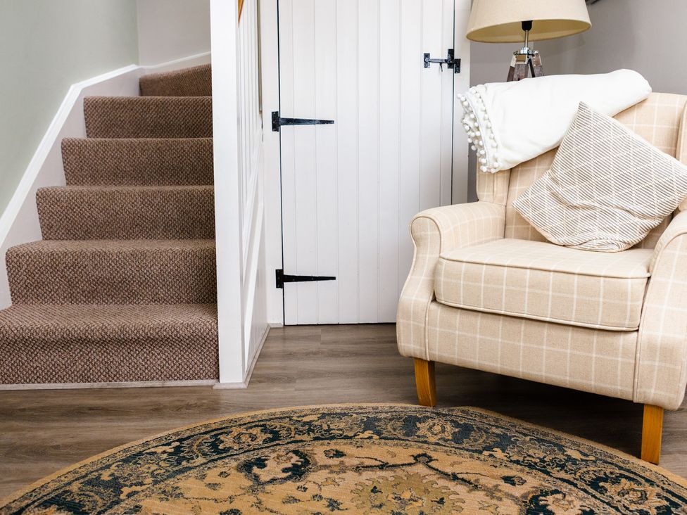 A living room with a chair and staircase at Eryri View Retreat in Llangoed near Beaumaris