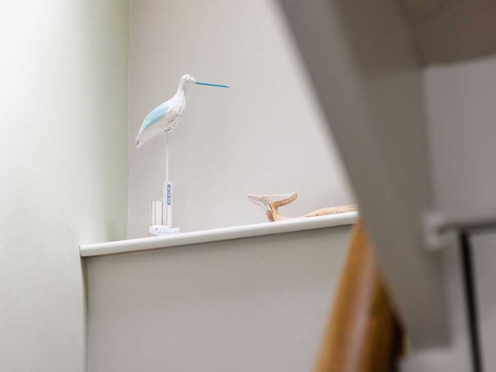 A decorative bird and whale tail on a shelf in a staircase at Eryri View Retreat in Llangoed near Beaumaris
