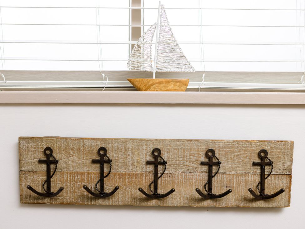 A wooden wall rack with anchor hooks and a decorative sailboat at Eryri View Retreat Llangoed near Beaumaris
