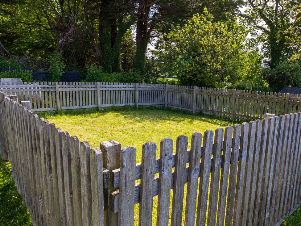 A fenced area with grass and trees at Eryri View Retreat Llangoed near Beaumaris