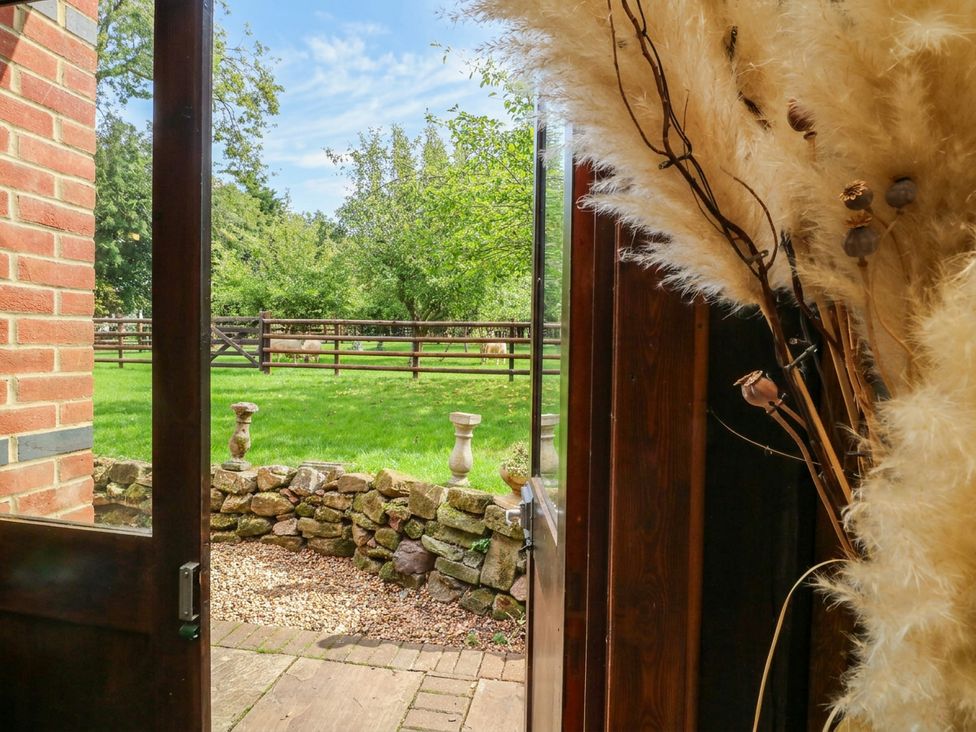 A view of a garden with a stone wall and fence at The Barn in Tamworth